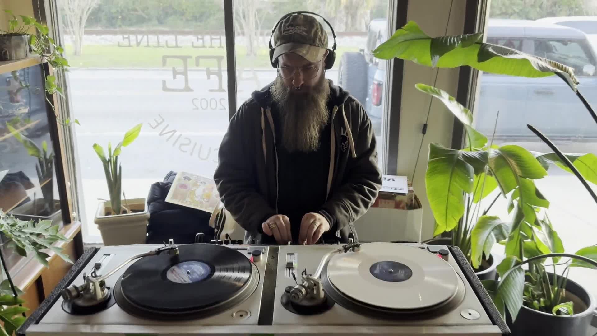 DJ spinning vinyl on two turntables in the window of End Of The Line Cafe